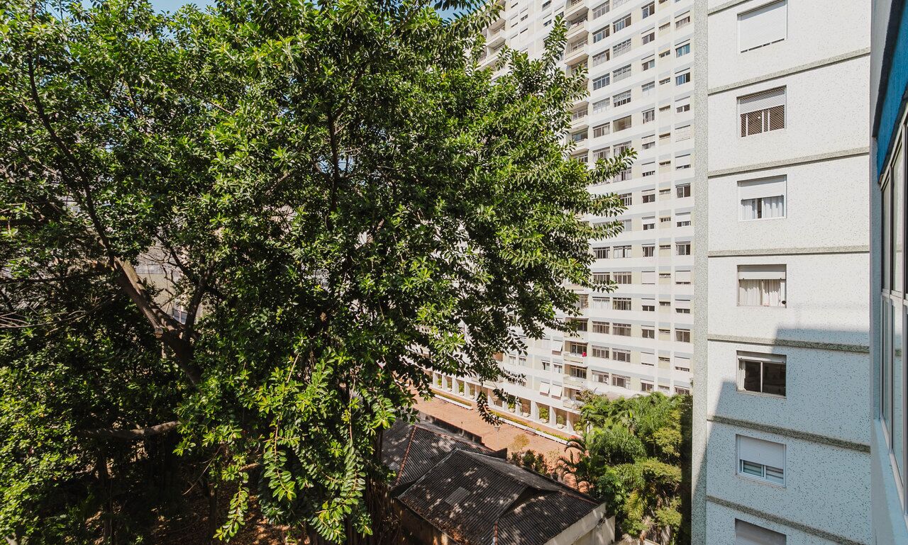 Un edificio alto con diversi piani, ampie finestre e un albero sullo sfondo.