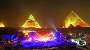 A nighttime view of a large pyramid complex with multiple pyramids illuminated by colorful lights. - Pharaonic Pyramids Hotel  (Giza)