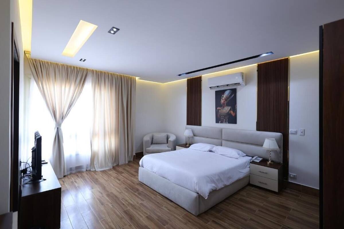 Un dormitorio moderno con una cama grande, mesitas de noche, un escritorio y un televisor.