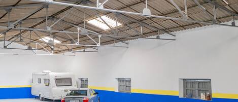An indoor parking area with a white and blue wall, a silver car, and a white RV.
