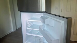 Un refrigerador de acero inoxidable con varios estantes transparentes y un compartimento congelador.