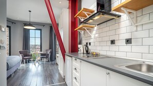 Una cocina moderna con armarios blancos, un lavamanos de acero inoxidable y una pared de acento roja.