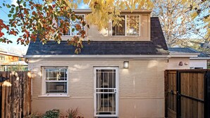 Une maison à deux étages avec une porte d’entrée, une petite fenêtre et une clôture en bois.