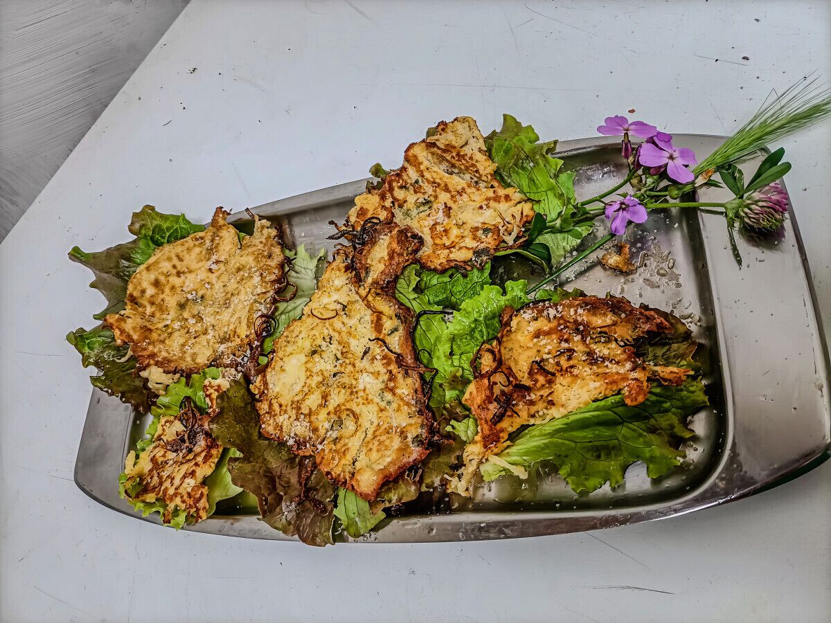A tray with grilled chicken and greens on a white surface.