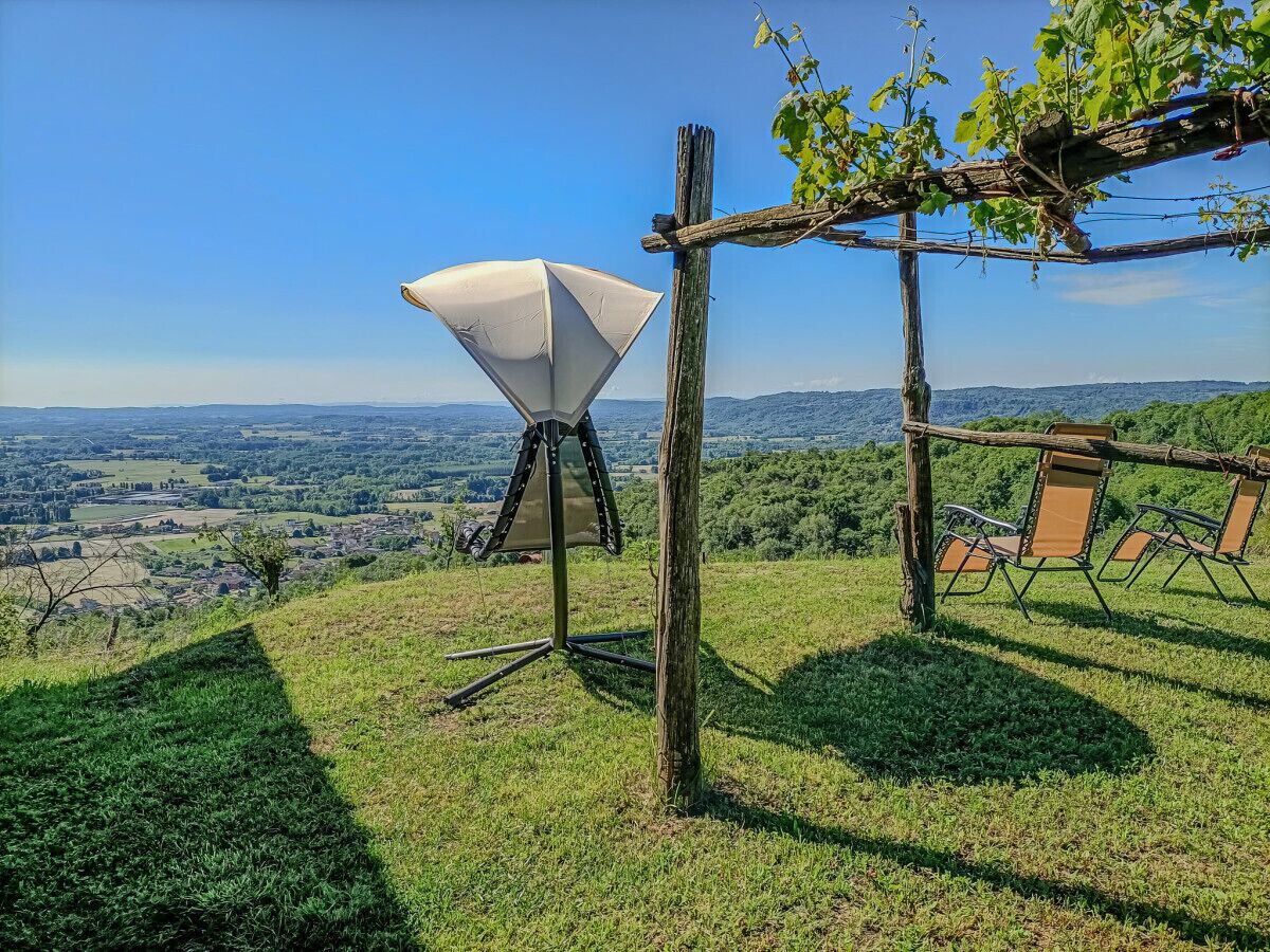 Een wijngaard met een witte parasolstructuur, houten pergola en buitenterras.