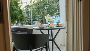 Ein Balkon mit rundem Tisch, zwei Stühlen, einer Blumenvase und einer Platte mit Gebäck.