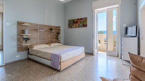 Ein Schlafzimmer mit Bett, Holz-Kopfteil, Gemälde, Fernseher und Balkontür.