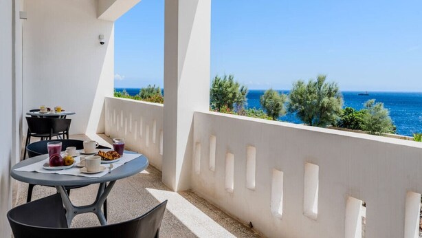 Ein Balkon mit Frühstückstisch, mit Blick auf die Küste.