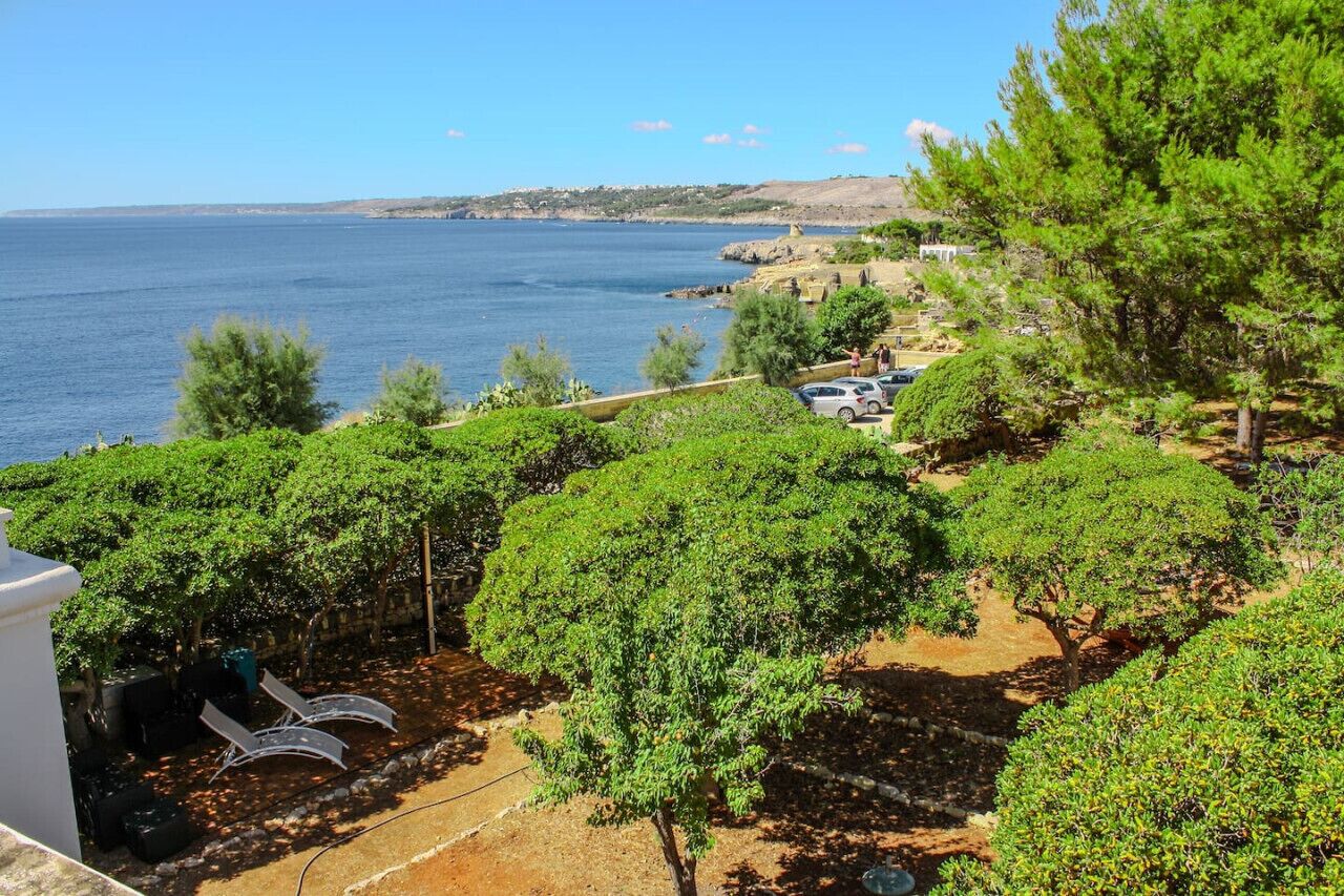 Une propriété située sur la côte, avec vue sur la mer, une zone aménagée avec des arbres et une voiture garée.