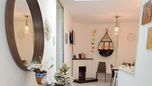 Un pasillo moderno con piso de mármol, un espejo grande y una consola de vidrio decorada con plantas.