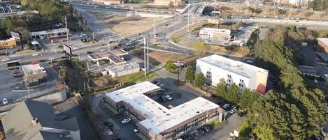 An aerial view of a commercial area with a large building, parking lots, and multiple roads.