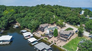 Une propriété au bord du lac, avec plusieurs bateaux amarrés, une grande maison dotée d’une terrasse et une pelouse bien entretenue.