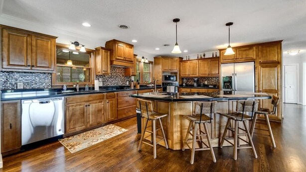 A spacious kitchen with wooden cabinets, a central island with bar stools, and built-in appliances. - Mountain View 4BR Home with Fireplace & Ping Pong (Franklin)