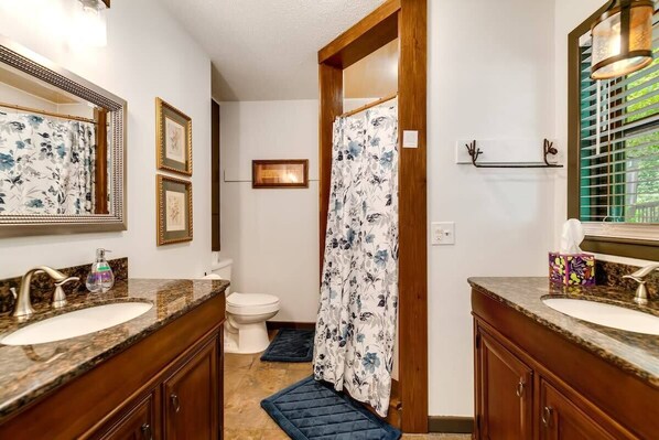 A bathroom with two sinks, a toilet, and a shower curtain. - Mountain View 4BR Home with Fireplace & Ping Pong (Franklin)