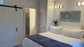 A bedroom with a large bed, a sliding door, a mirror, and a potted plant. - Posto Felice! Carillon Beach (Panama City Beach)