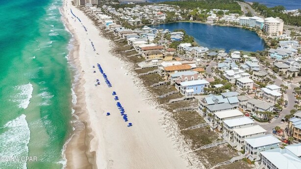 An aerial view of a coastal area with a long sandy beach, a marina, and residential buildings. - Posto Felice! Carillon Beach (Panama City Beach)
