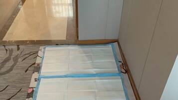 Una habitación con suelo de baldosas, un tapete estampado y un colchón blanco sobre el piso.