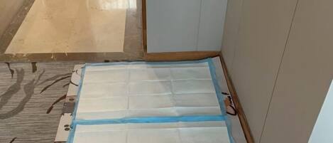 A room with a tiled floor, a patterned rug, and a white mattress on the floor.