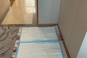 Una habitación con suelo de baldosas, un tapete estampado y un colchón blanco sobre el piso.