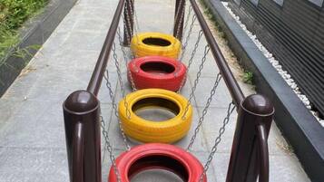 A series of tire swings suspended by chains, with a metal railing in the foreground.