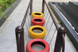 A series of tire swings suspended by chains, with a metal railing in the foreground.
