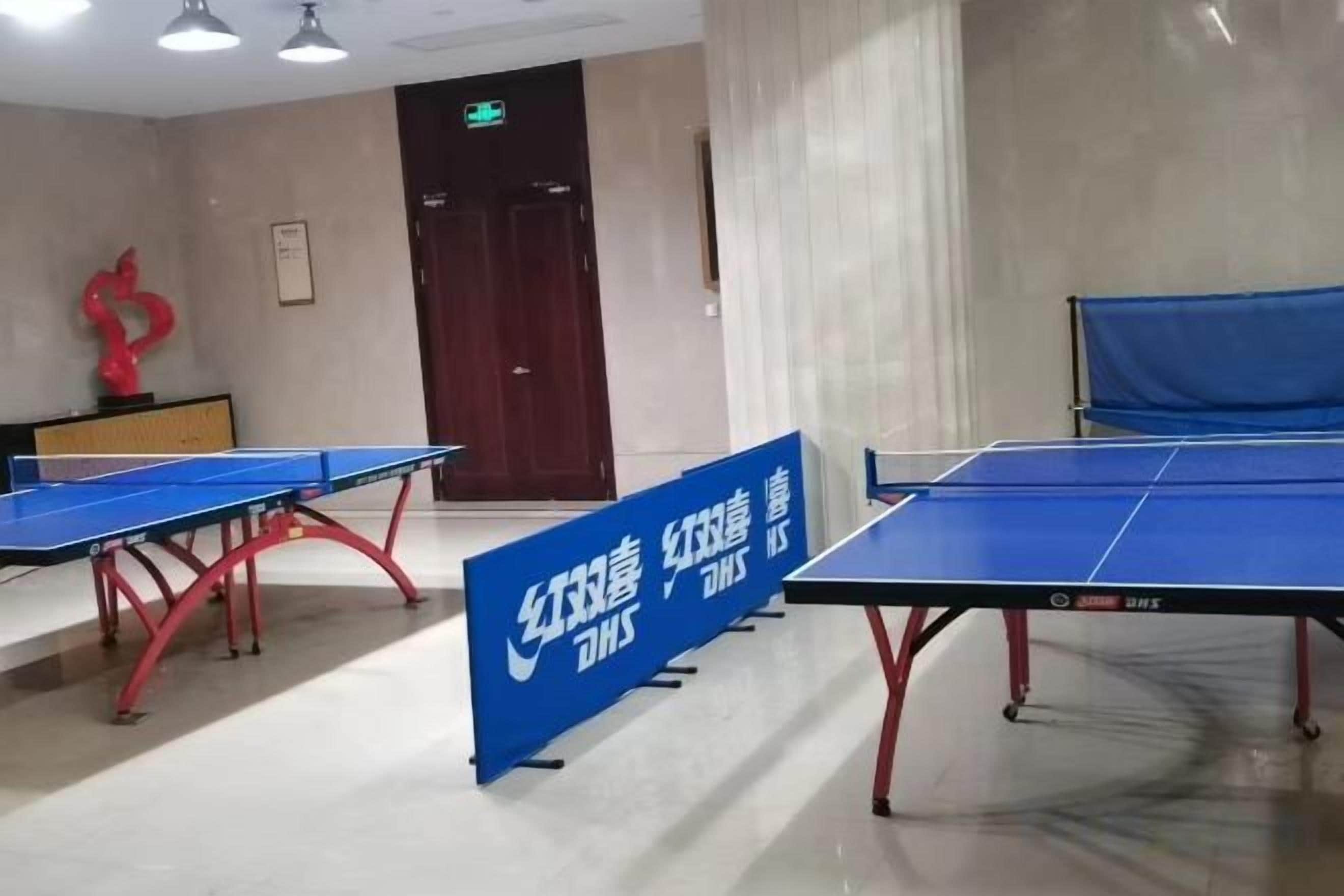 A room with ping pong tables and a blue banner with text.