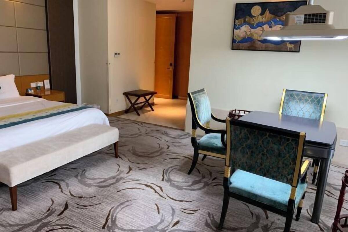 Una camera d'albergo con un letto, una scrivania, una sedia e un tavolino.