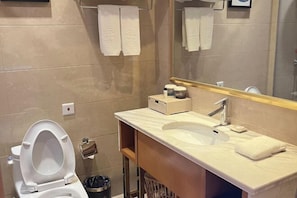 Un baño moderno con inodoro, lavamanos, espejo y toallero.