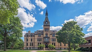 A large, historic building with a prominent clock tower, surrounded by well-maintained lawns and trees. - Midway Marvel: Central Location, Walk to Light Rail, Fast WiFi, Free Parking (Saint Paul)