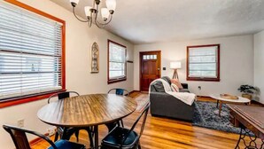 A living room with a round wooden table, a sofa, and a chandelier. - Ancient City Cottage (St. Augustine)