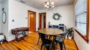 A dining area with a wooden table and chairs, a chandelier, and a wreath on the wall. - Ancient City Cottage (St. Augustine)