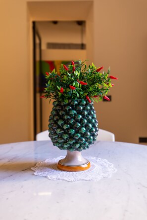 En vas formad som en ananas, med röda blommor på ett marmorbord.
