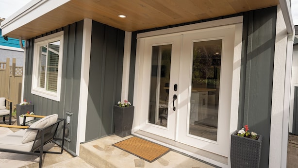 A house with a covered patio, a sliding glass door, and a small outdoor seating area. - Serenity: Rockcliffe Getaway (Oliver)