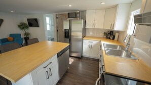 A modern kitchen with white cabinets, stainless steel appliances, and a wooden countertop. - Serenity: Rockcliffe Getaway (Oliver)
