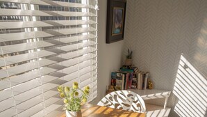 A dining area with a wooden table and white chairs, a potted plant, and books on a shelf. - Serenity: Rockcliffe Getaway (Oliver)