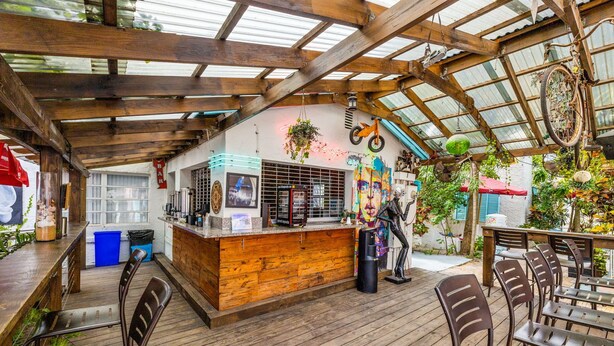 Un área de bar al aire libre con mobiliario de madera y techo rústico.