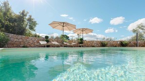 Ein klarer Swimmingpool mit Liegestühlen und Sonnenschirmen.