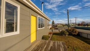 A single-story house with a yellow door, a wooden deck, and a clear sky. - Aoraki Oasisl, FREE WIFI & SKY TV (Twizel)