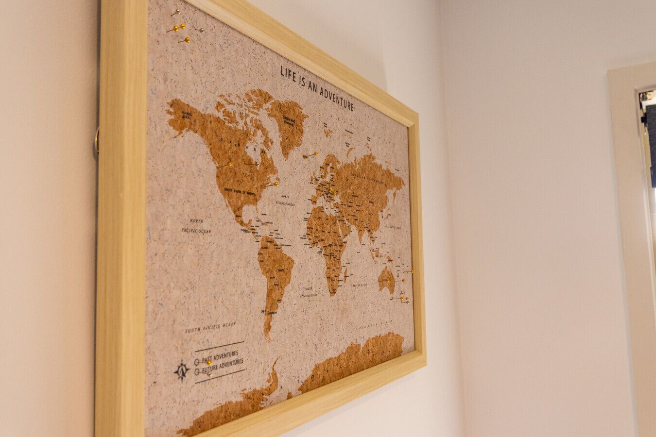 A corkboard map titled "Life is an Adventure" with pins marking locations.