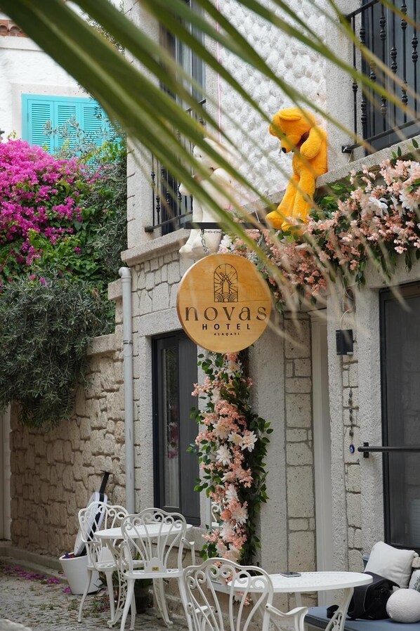 A hotel sign with a yellow teddy bear and floral decorations. - Novas Hotel Alaçatı (Cesme)