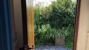 Ein Durchgang zu einem Garten mit gefliestem Boden und einem schmiedeeisernen Tor.