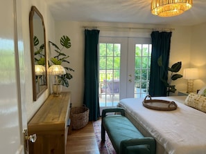 A bedroom with a bed, bedside table, lamp, and a view of the outdoors. - Casita Encanta-Dora, Steps to town, Pet-Friendly (Mount Dora)