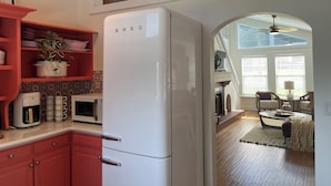 A kitchen with a white refrigerator, red cabinets, and a tiled backsplash. - Charming 2-bedroom cottage in downtown Mount Dora with RV parking, pets welcome  (Mount Dora)