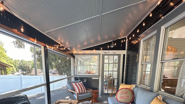 A covered outdoor seating area with wicker furniture, a patterned rug, and string lights. - Charming 2-bedroom cottage in downtown Mount Dora with RV parking, pets welcome  (Mount Dora)