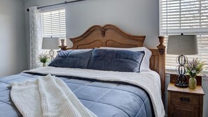 A bed with a wooden headboard, two bedside lamps, and a small nightstand with a vase. - Private Farmhouse Retreat in Shoal Creek (Exeter)