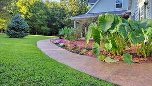 A well-maintained garden with a curved pathway leading to a house. - Private Farmhouse Retreat in Shoal Creek (Exeter)
