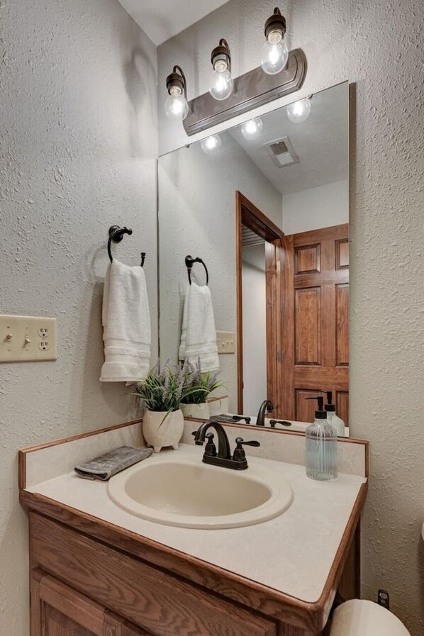 A bathroom with a wooden vanity, a large mirror, and a light fixture above the mirror. - Rural 6 bedroom cabin - With a Hot Tub! (Exeter)