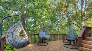 Une terrasse en bois avec trois chaises suspendues et un escalier en bois.