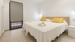 Une chambre à coucher comprenant un lit, une table de chevet, une lampe fixée au mur et une porte coulissante.