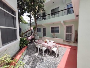 A courtyard with a table and chairs, surrounded by a low wall and plants. - Cozy One Bedroom Apartment in Juan Dolio Beach with AC, WiFi & Hot Water (Playa Juan Dolio)